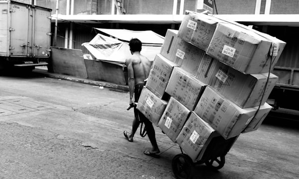 Man pushing a cart stacked with boxes through the street