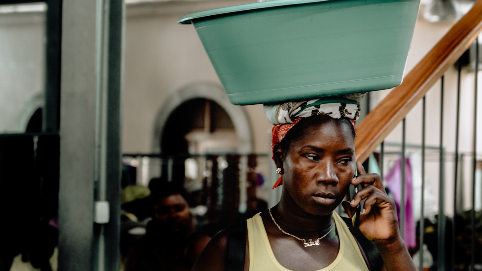 A trader on her phone with a basin balanced on her head