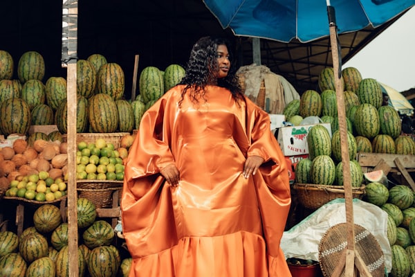 Market woman in an orange dress arranging fruit at her stall